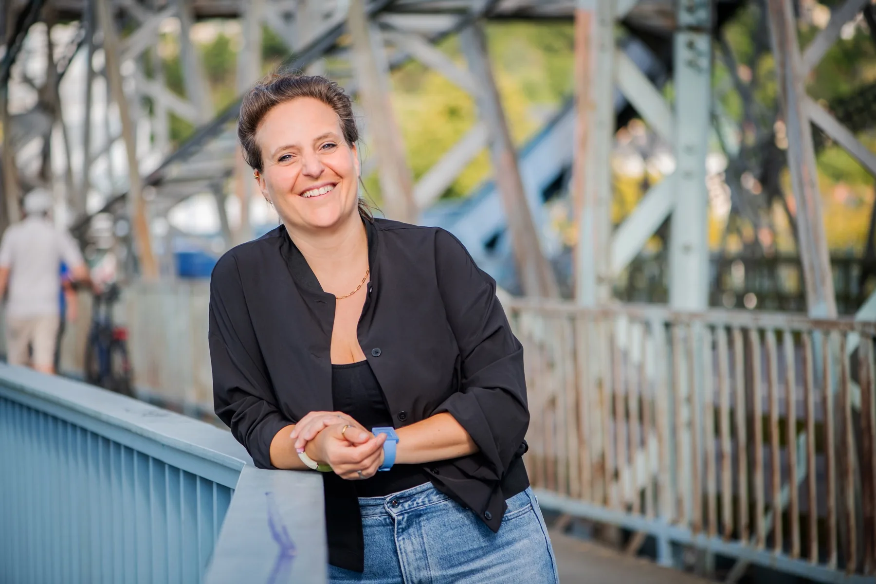 Freie Rednerin Annette Krönert lehnt lächelnd am Geländer einer Stahlbrücke