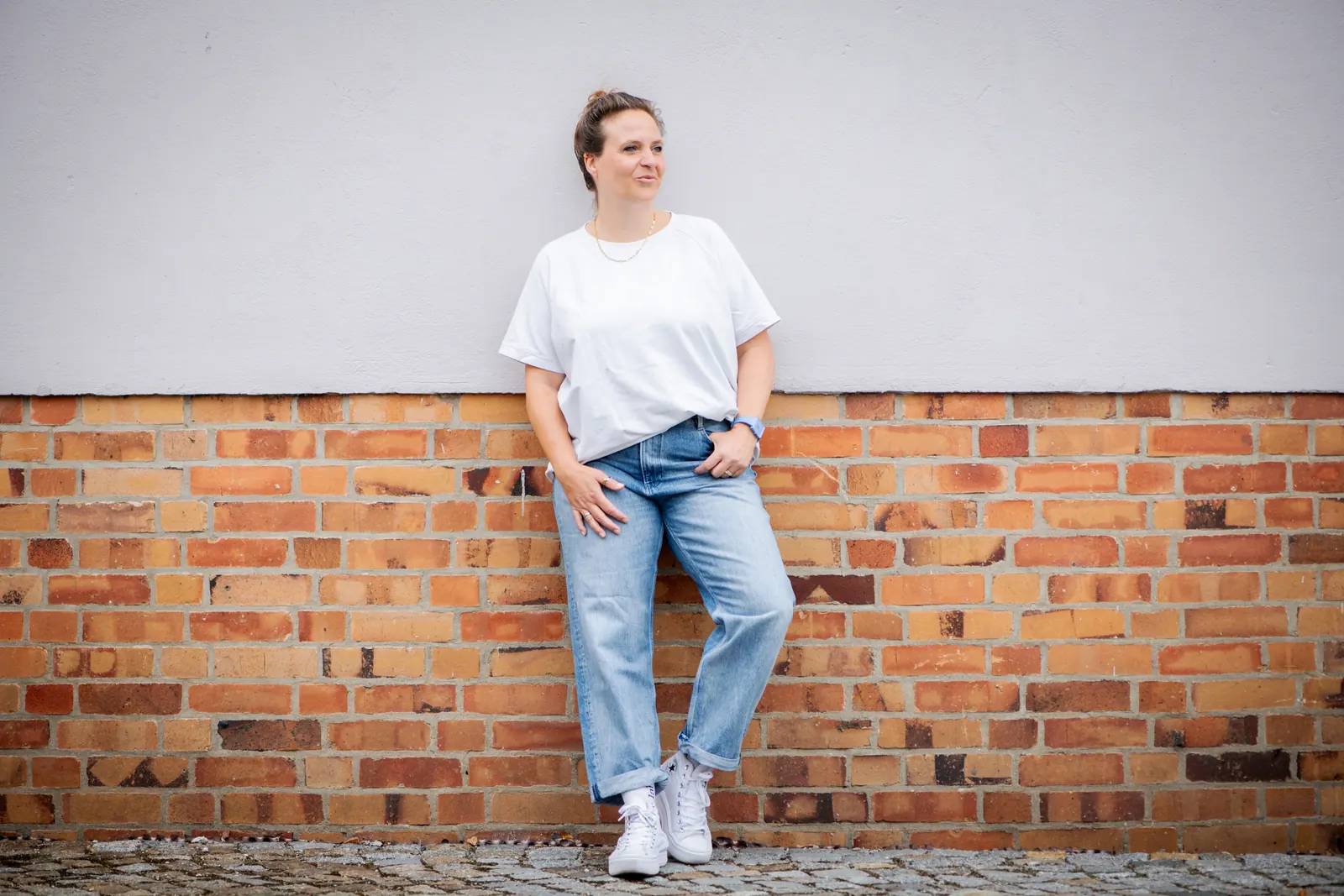 Annette Krönert lehnt lächelnd an einer Backsteinwand