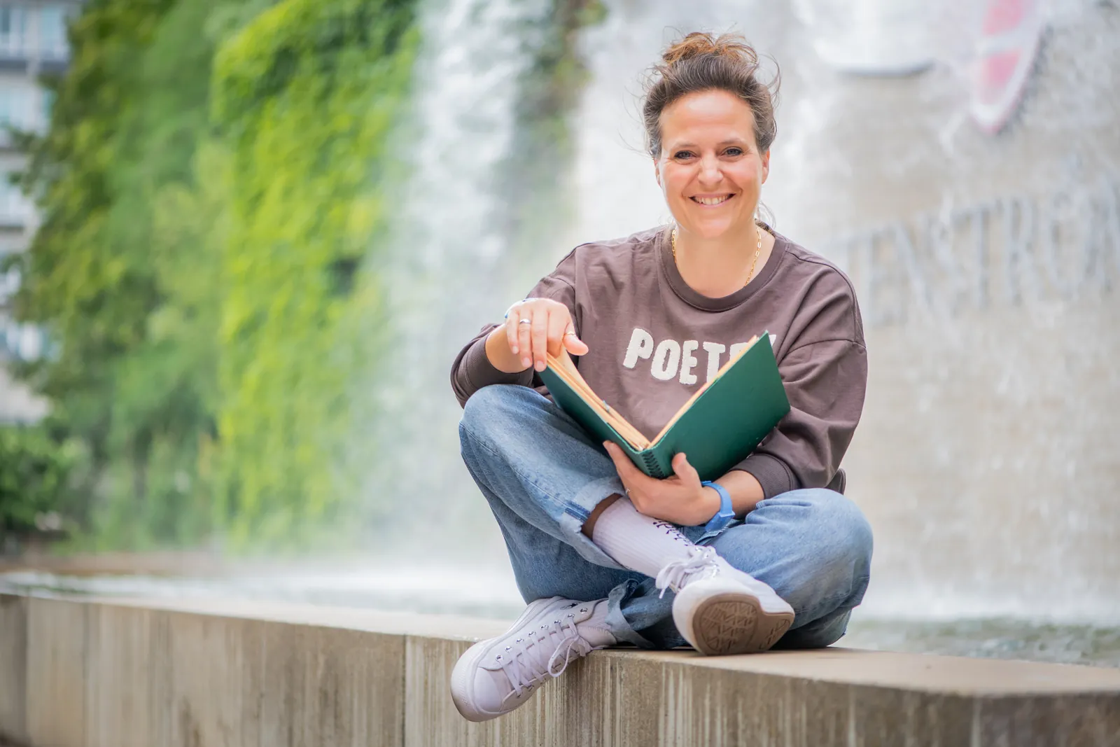 Freie Rednerin Annette Krönert sitzt mit einem Buch an einem Brunnen